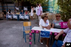 Supporters of "yes," right, and of "no," left, wait for voters arriving in a polling station in Athens, July 5, 2015.