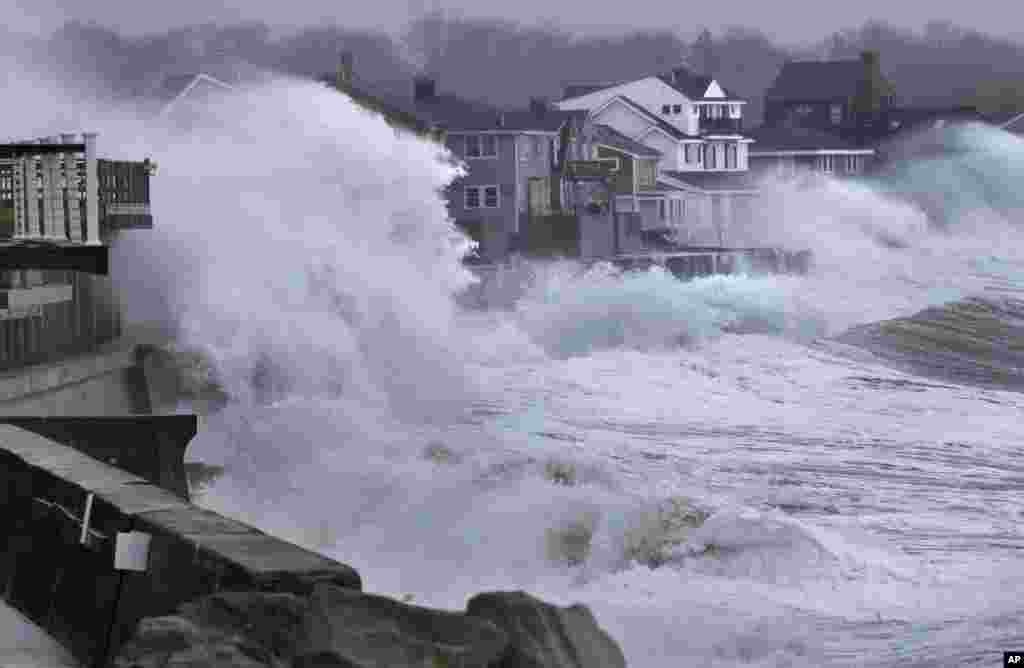 Gelombang laut menabrak dinding pembatas pantai dan masuk ke rumah-rumah di sepanjang pantai Scituate, Massachusetts, AS.