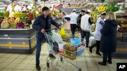  FILE - A man pushes a cart with food items at a grocery store in Moscow, Russia, April 2, 2015.