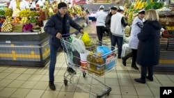  FILE - A man pushes a cart with food items at a grocery store in Moscow, April 2, 2015.