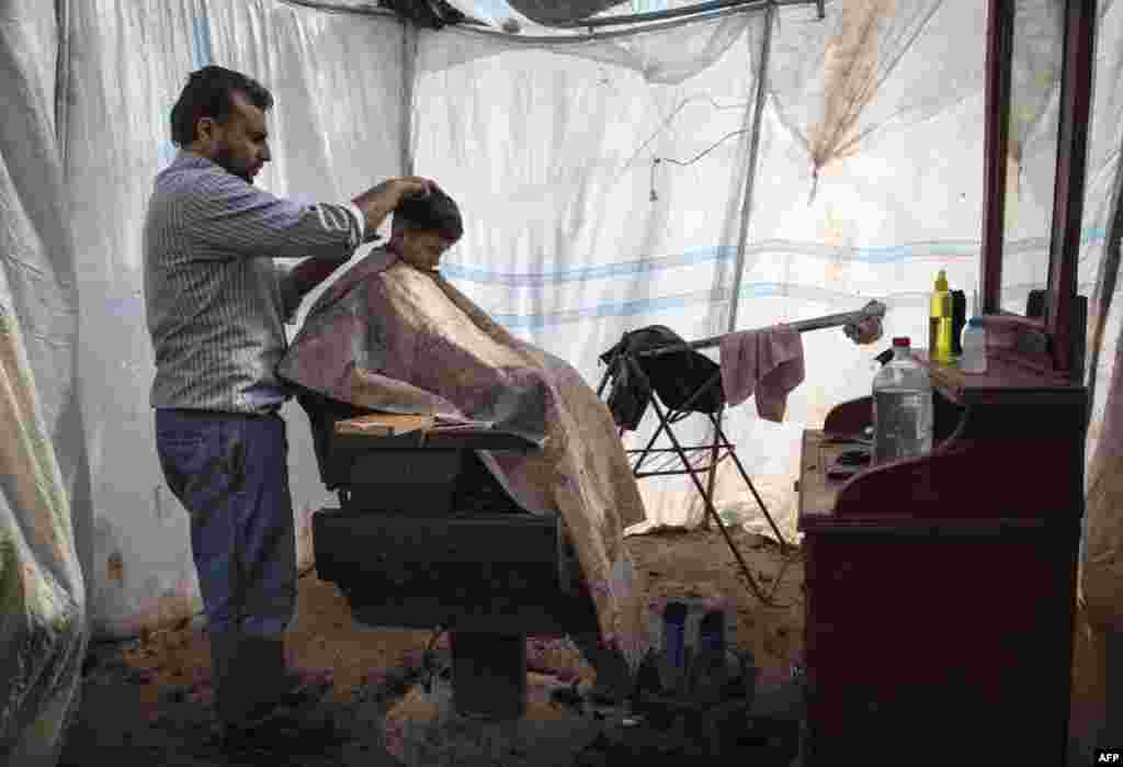 A boy gets his hair cut at a makeshift barber shop at the Azaz refugee camp along the Syrian-Turkish border, February 19, 2013.