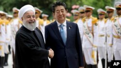 Perdana Menteri Jepang Shinzo Abe (tengah) berjabat tangan dengan Presiden Iran Hassan Rouhani dalam upacara penyambutan resmi di Istana Saadabad, Teheran, Iran, 12 Juni 2019.
