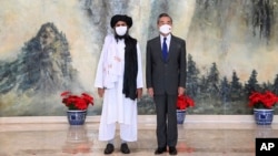 ARCHIVO - En esta foto del 28 de julio de 2021 publicada por la Agencia de Noticias Xinhua de China, el cofundador de los talibanes, Mullah Abdul Ghani Baradar, a la izquierda, y el ministro de Relaciones Exteriores de China, Wang Yi, posan para una foto en Tiajin, China.