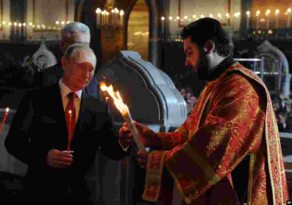 Russian President Vladimir Putin, foreground left, attends the Easter service in Christ the Savior Cathedral in Moscow, Russia, April 20, 2014. 