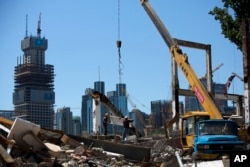 FILE- Workers move a steel frame on a demolished site for a new development project at the central business district of Beijing, China on June 30, 2015.