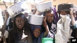 Displaced Somali children line up, containers in hand, to receive food aid in Mogadishu, March 15, 2011