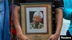 Một người cầm bức ảnh cựu Tổng thống Nelson Mandela trong ngày tang lễ của ông