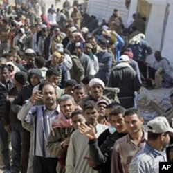 People who used to work in Libya and fled the unrest in the country, wait to receive clothes, at the Tunisia-Libyan border, in Ras Ajdir, Tunisia, Mar 3 2011
