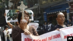Parishioners of Thai Ha church hold a crucifix and anti-government banners while marching in Hanoi, November 18, 2011.
