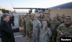 FILE - Poroshenko, left, speaks with U.S. servicemen who delivered counterbattery radars for the Ukrainian army in Lviv, Ukraine, Nov. 14, 2015.