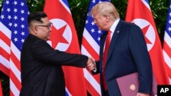 Pemimpin Korea Utara, Kim Jong Un (kiri) dan Presiden AS Donald Trump dalam pertemuan di Singapura, 12 Juni lalu. 