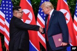 FILE - North Korea leader Kim Jong Un and U.S. President Donald Trump shake hands at the conclusion of their meetings at the Capella resort on Sentosa Island Tuesday, June 12, 2018 in Singapore.