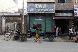 A man walks with a chair on his head outside a shuttered restaurant in Mathura town, in the northern state of Uttar Pradesh, India, Jan. 24, 2022.