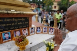 FILE PHOTO - A man prays in front of portraits of victims of a fatal 1997 grenade attack on an opposition rally, which are displayed during a ceremony to remember the victims, at a monument in Phnom Penh, Cambodia, March 30, 2018. REUTERS/Samrang Pring