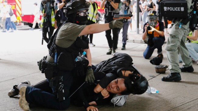 香港警察在逮捕一名参加反对港版国安法游行示威者的同时举起手中的胡椒喷剂手枪。(2020年7月1日)