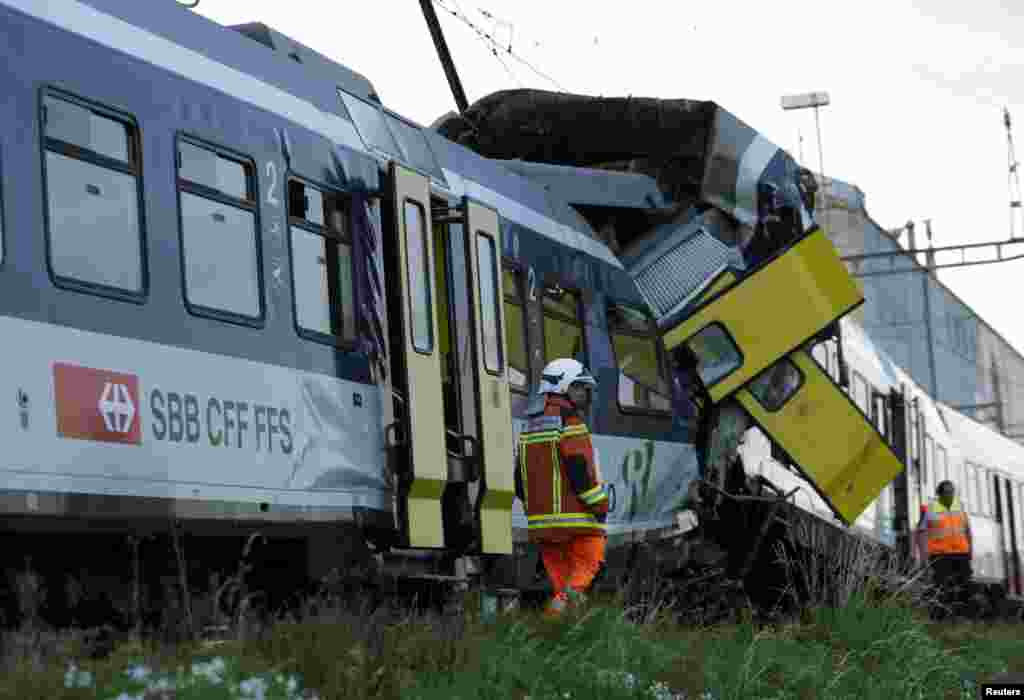 Rescue workers at the site of a head-on collision between two trains near Granges-pres-Marnand, Switzerland, July 29, 2013. 