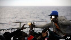 Migrants share slices of bread on the deck of the Belgian Navy vessel Godetia after they were saved at sea during a search and rescue mission in the Mediterranean Sea off the Libyan coasts, June 24, 2015