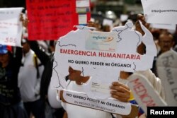 FILE - Reinaldo Olivares, a kidney transplant patient, holds a placard with the shape of the map of Venezuela that reads, "Humanitarian emergency. I do not want to lose my organ," during a protest against medicinal shortages in Caracas, Venezuela, Feb. 8,