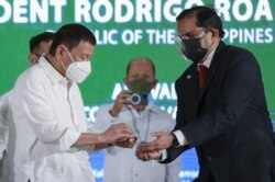 Presiden Filipina Rodrigo Duterte (kiri) menerima botol vaksin AstraZeneca dari Perwakilan Organisasi Kesehatan Dunia (WHO) di Filipina Dr. Rabindra Abeyasinghe, setibanya di Pangkalan Udara Villamor, Metro Manila, Filipina, Kamis, 4 Maret 2021. Alfred Frias/Malacanang Presidential Photographers Division via AP)