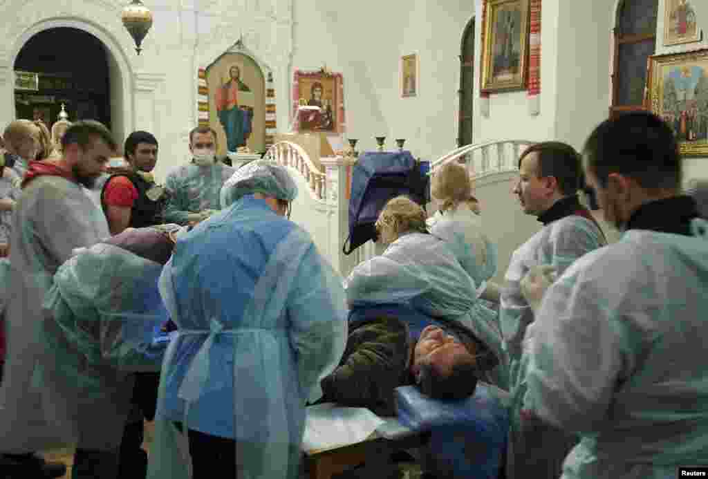 Um homem que foi ferido durante os confrontos entre manifestantes, membros do Ministério do Interior e Polícia de choque, recebe tratamento médico dentro da Catedral Mikhailovsky Zlatoverkhy (Mosteiro de São Miguel das Cúpulas Douradas), Kiev, Fev. 19, 2014.
