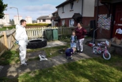 Russel Bowers, seorang relawan (kanan), mengantar makanan untuk Becky Foster (32), dan kedua anaknya di Edinburgh, Skotlandia, di tengah pandemi virus corona, 22 April 2020. (Foto: AFP)