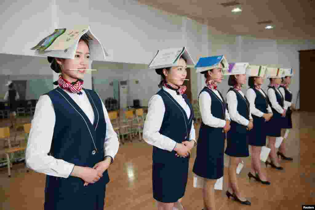 Para siswi sekolah pramugari melakukan latihan posisi berdiri sambil tersenyum (menggigit sumpit) dan menjepit kertas di kakinya, pada sekolah pramugari di Shijiazhuang, Hebei, China.