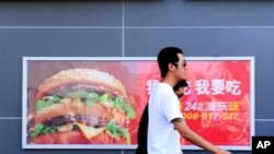 Two Chinese men walk past a billboard advertising US fast-food giant McDonald's, in Yichang, central China's Hubei province, 8 July, 2010.