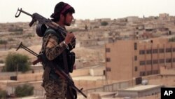 This photo provided by the Syria Democratic Forces (SDF) shows a fighter from the SDF carrying weapons as he looks toward the northern town of Tabqa, Syria, April 30, 2017.