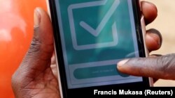 Un chauffeur de moto-taxi, connu sous le nom de boda-boda, du réseau SafeBoda, utilise son téléphone portable pour effectuer une transaction avec un client dans une rue de Kampala, en Ouganda, le 5 octobre 2018.