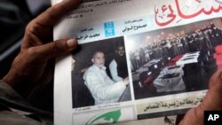 Seorang warga Mesir tengah memegang surat kabar Al-Ahram di Kairo, Mesir (20/8) yang menampilkan gambar pemimpin Ikhwanul Muslimin Mohammed Badie (kiri) di halaman depan (Foto: dok). Pengadilan Mesir menunda sidang atas Muhammad Badie dan dua wakilnya, Minggu (25/8).