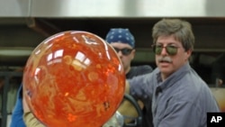 Glass artist Josh Simpson turns one of his signature planet-like spheres after heating it in a furnace. 