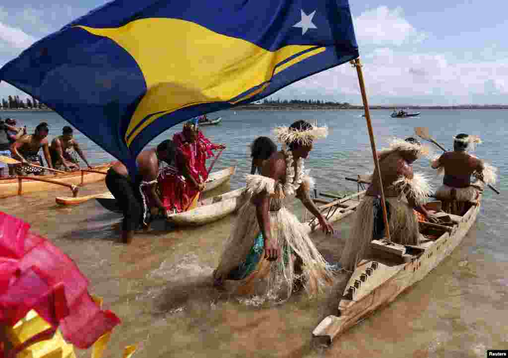 Representatives from South Pacific nations dress in traditional attire while pushing their canoes into the water, as they prepare to protest against ships leaving the Newcastle coal port, located north of Sydney, Australia. Around 100 demonstrators protested the world&#39;s largest coal port, demanding a global change to the use of coal. 