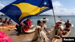 Traditionally-dressed representatives from South Pacific nations push their canoes into the water as they prepare to participate in a protest aimed at ships leaving the Newcastle coal port, located north of Sydney, Australia, Oct. 17, 2014.