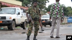 FILE - A Burundian soldier with his gun and rocket launcher guard a deserted street in Bujumbura, Burundi, Nov. 8, 2015. 