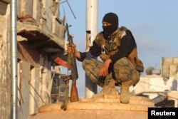FILE - A member of al-Qaida's Nusra Front carries his weapon as he squats in the town of the northwestern city of Ariha, after a coalition of insurgent groups seized the area in Idlib province May 29, 2015.