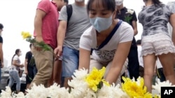 Warga kompleks apartemen Harbour City meletakkan bunga di memorial dekat gedung tempat tinggal mereka untuk para korban ledakan di Tianjin (18/8). (AP/Paul Traynor) 