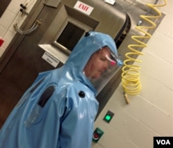 Dave Harbourt, a USAMRIID biosafety officer demonstrates how to put on and work in an anti-containment suit at a training lab at USAMRID. Dec. 11, 2014. (VOA/CMaddux)