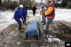 Cemetery personnel lower the casket containing the body of 82-year-old James Oram, who died in a local nursing home and whose body was unclaimed, into his unmarked grave on the perimeter of Hope Cemetery in Worcester, Massachusetts, Feb. 1, 2018.