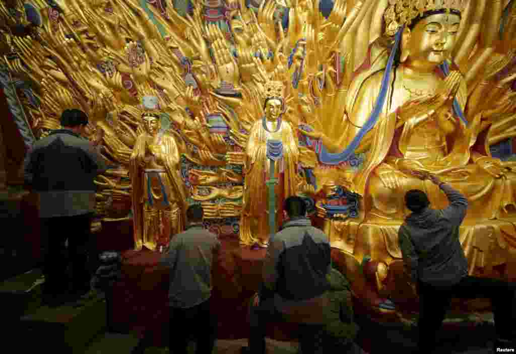 Para pekerja mengecat lapisan emas di&nbsp;​Bodhisattva di Chongqing, China.