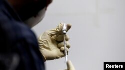 Un médecin remplit une seringue de COVAXIN, un vaccin expérimental COVID-19 soutenu par le gouvernement indien, avant de l'administrer à un agent de santé lors de ses essais, à la Gujarat Medical Education and Research Society à Ahmedabad, en Inde, le 26 novembre 2020.