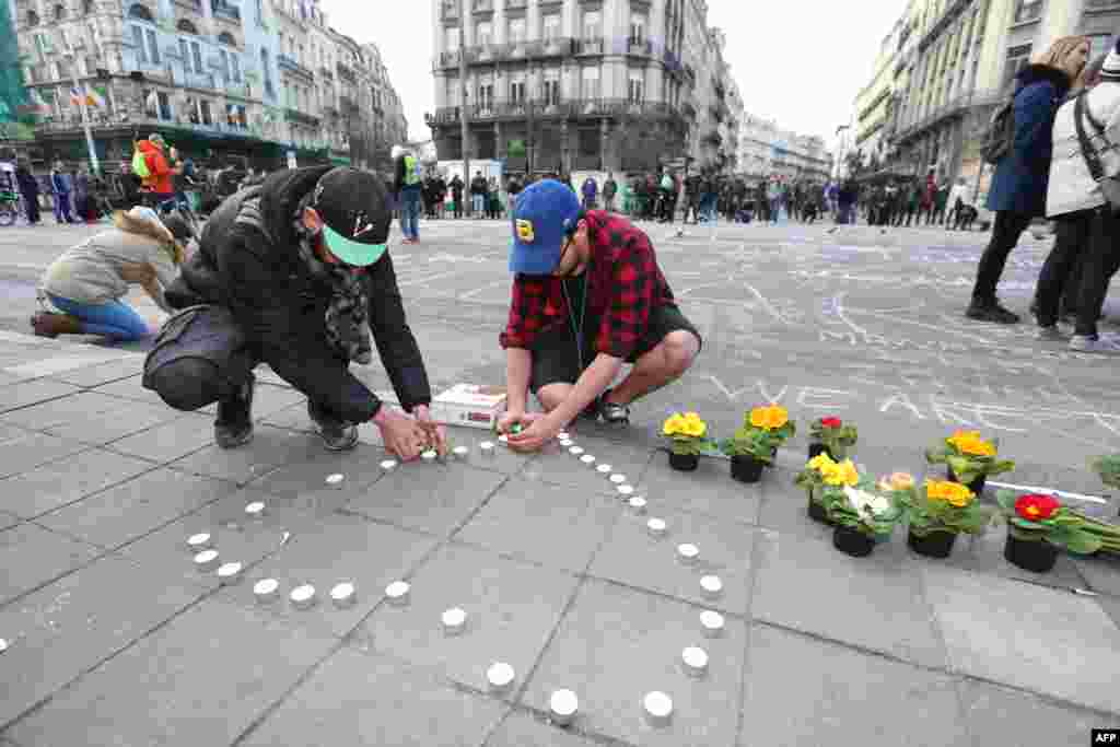 People leave candles and flowers in tribute to victims of triple bomb attacks in front of the stock exchange building in the city center of Brussels on March 22, 2016. 