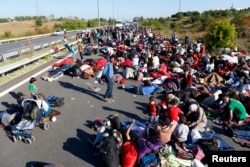 FILE - Men, women and children gather on a highway which is blocked by Turkish police and gendarmes near Edirne, Turkey, Sept. 19, 2015.