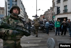 French soldiers secure the area as shots are exchanged in Saint-Denis, France, near Paris, Nov. 18, 2015, during an operation to catch fugitives from Friday night's deadly attacks in the French capital.