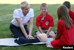 Monaco's Princess Charlene, goodwill ambassador for the International Federation of Red Crosses and Red Crescents Societies (IFRC) for first aid, demonstrates on a dummy how to practice first aid to chidren during the launch of World First Aid Day 2016 at the United Nations in Geneva, Sept. 9, 2016.