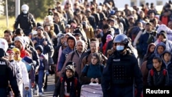 Slovenian police officers guide migrants towards the Austrian border town of Spielfeld, in the village of Sentilj, Nov. 18, 2015. 