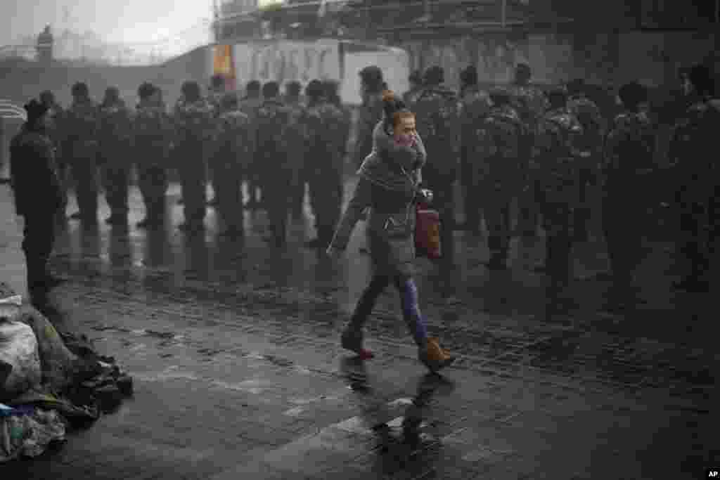 A woman passes by Ukrainian recruits receiving military instructions in Kyiv's Independence Square, March 4, 2014.