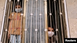 Des enfants portant des masques de protection pendant un couvre-feu pour limiter la propagation du coronavirus à Sanaa, au Yémen, le 6 mai 2020.
