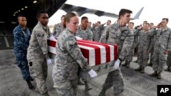 In this Sept. 13, 2018 photo, military personnel carry flag-draped transfer cases containing remains of unidentified service members to waiting trucks, at Offutt AFB in Bellevue, Neb. The remains were gathered through various DPAA missions in Europe.