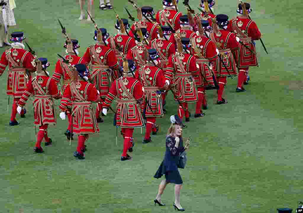 Soldiers walk past a guest as Britain&#39;s Queen Elizabeth II hosts a Garden Party at Buckingham Palace in London