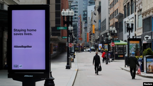 Peatones caminan por la zona comercial casi vacía de Downtown Crossing (centro de Boston) después de que el gobernador de Massachusetts, Charlie Baker, extendiera la orden de permanencia en el hogar y de cerrar negocios no esenciales hasta el 18 de mayo debido a la COVID-19.
